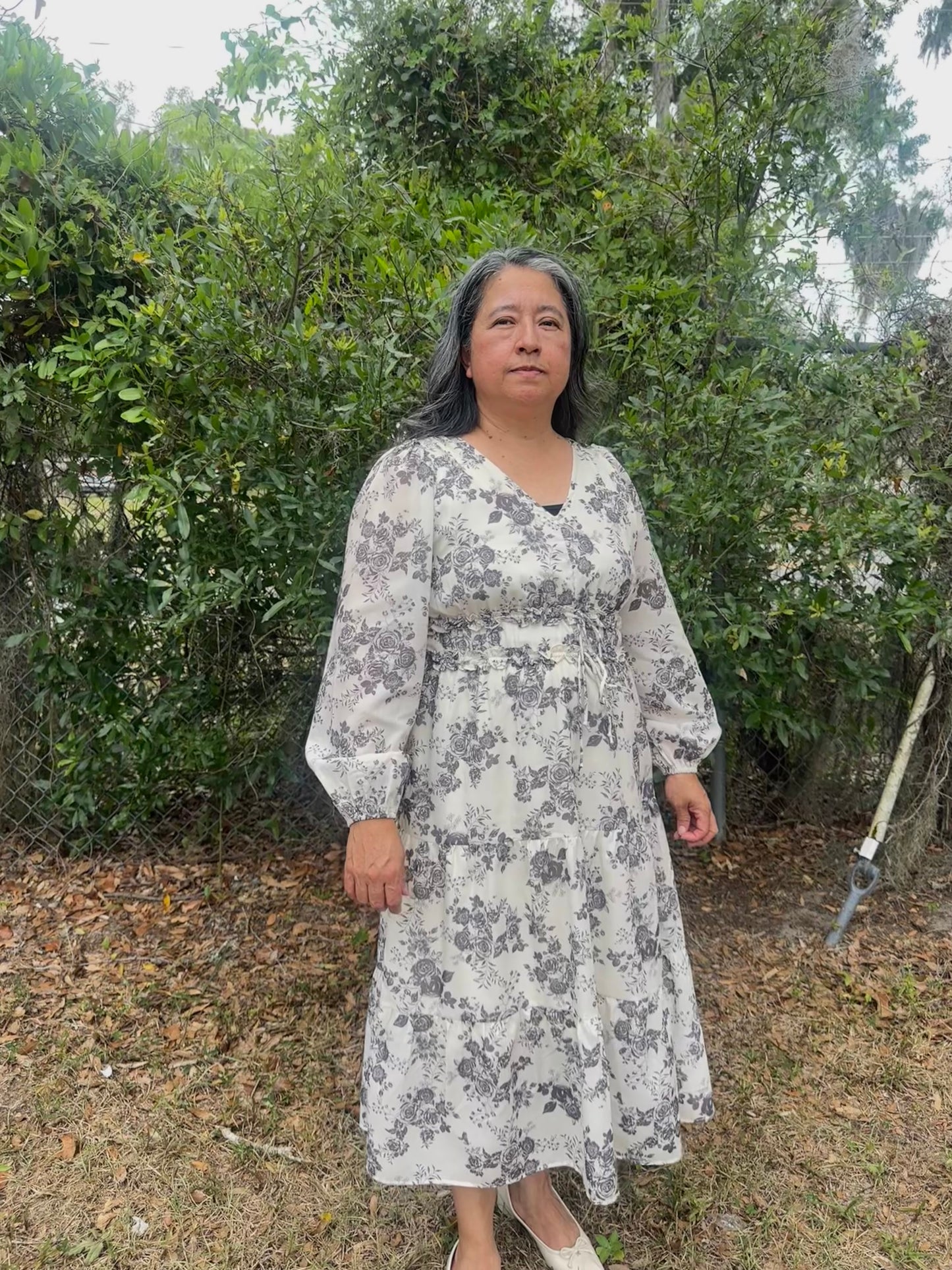 Woman wearing a floral dress standing in front of greenery