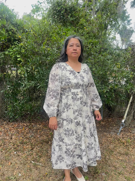 Woman wearing a floral dress standing in front of greenery